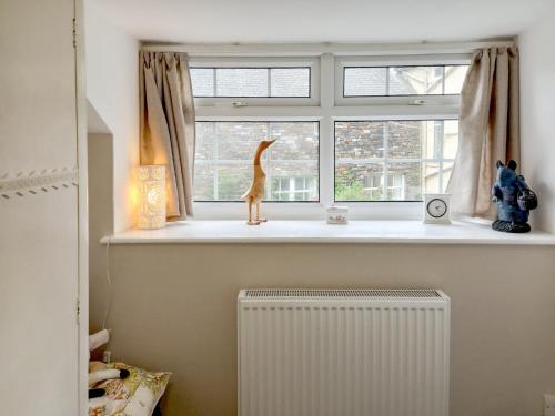 a window sill with a cat statue sitting in a window at 1 Tower Cottage in Portinscale