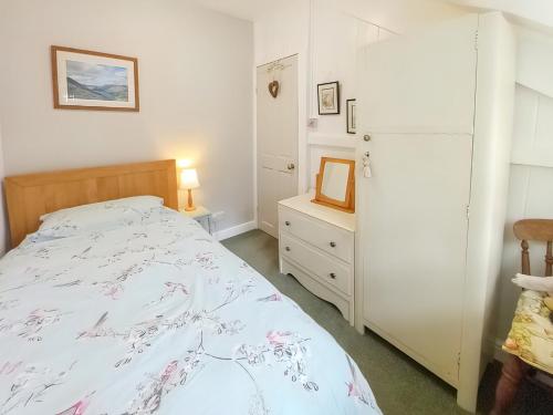 a bedroom with a bed and a white refrigerator at 1 Tower Cottage in Portinscale