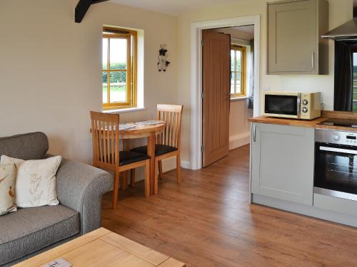 een keuken en een woonkamer met een bank en een tafel bij Saddlers Cottage in Alkham