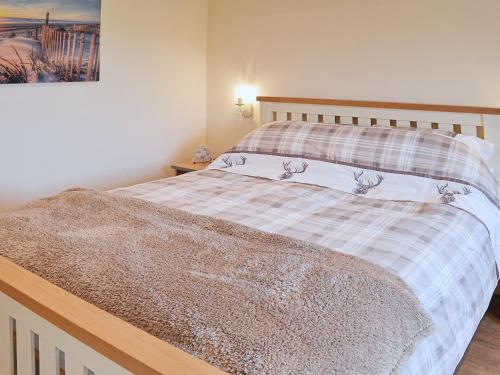 1 dormitorio con 1 cama con manta a cuadros en Saddlers Cottage, en Alkham