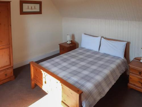 a bedroom with a bed with a checkered blanket and two night stands at Old Barn Farmhouse in Uplawmoor