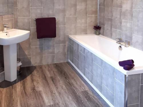 a bathroom with a bath tub and a sink at Old Barn Farmhouse in Uplawmoor