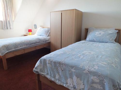 a bedroom with two twin beds and a dresser at Olafs Cottage in Garlieston