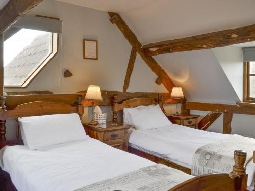 two beds in a room with a window at Stocks Tree Cottage in Preston Wynne