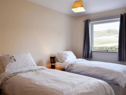 two beds in a room with a window at Booth Farm Bungalow in Hollinsclough