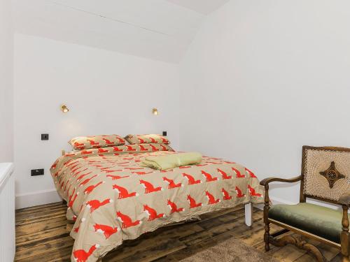 a bedroom with a bed with a comforter and a chair at Ty Sam in Llanwnda