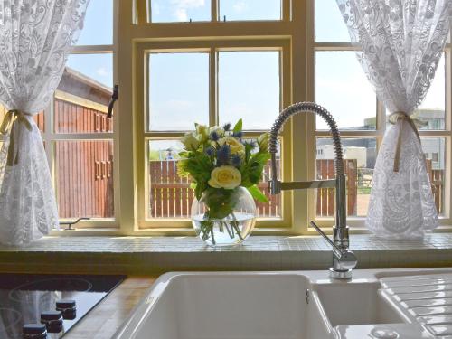 zlew kuchenny z wazą kwiatów obok okna w obiekcie Tickton Hall Cottage w mieście Tickton