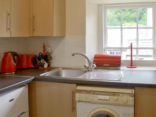 a kitchen with a sink and a washing machine at Kingfisher Apt - B4866 in Saint Cleer
