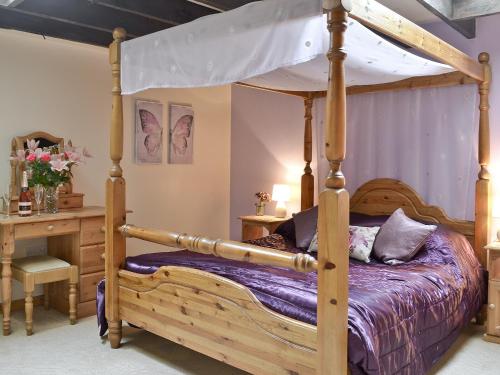 a bedroom with a wooden bed with a canopy at Burns Cottage in Drumnadrochit