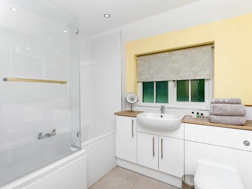 a white bathroom with a sink and a shower at Graces Cottage in Port of Menteith