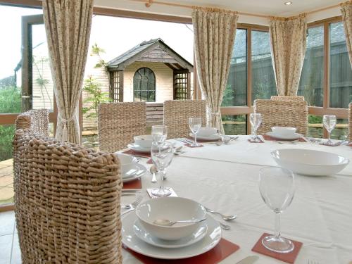 una mesa con sillas y un mantel y gafas blancos en Magnolia Cottage en Aberaeron