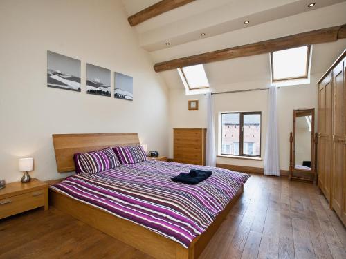 a bedroom with a large bed in a room with windows at The Cowshed in Froghall