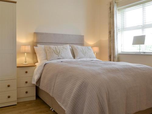 a bedroom with a large bed and a window at Kestral Cottage in Shotton