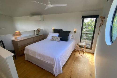 a bedroom with a white bed and a window at Hilltop Woods Noosa in Tinbeerwah