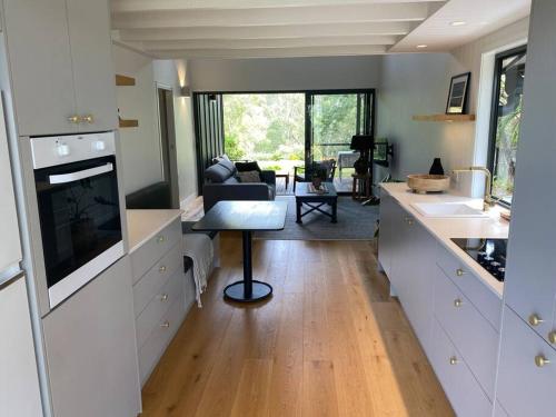 a kitchen with white cabinets and a living room at Hilltop Woods Noosa in Tinbeerwah