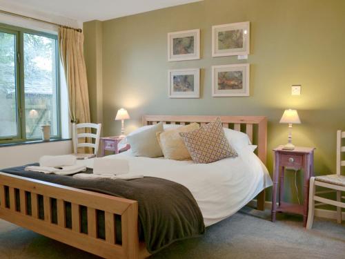 um quarto com uma cama grande com lençóis brancos e almofadas em The Roost em Blisland