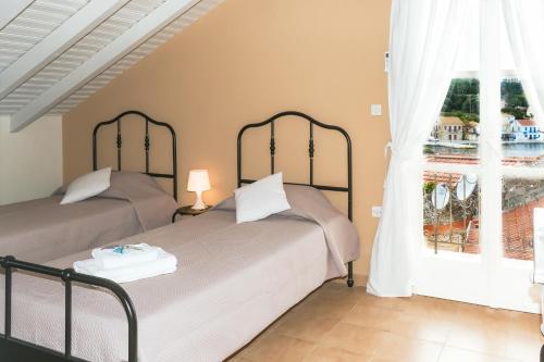 two beds in a room with a window at Captain's Quarters at Fiscardo Waterfront-feel the breeze in Fiskardho