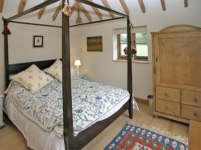 a bedroom with a four poster bed and a dresser at Coblye Barn in Brightling