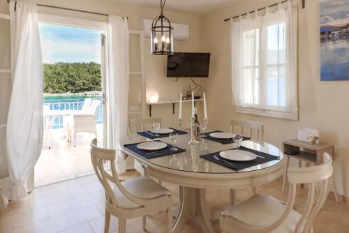 comedor con mesa, sillas y ventana en Captain's Quarters at Fiscardo Waterfront-feel the breeze, en Fiskardho