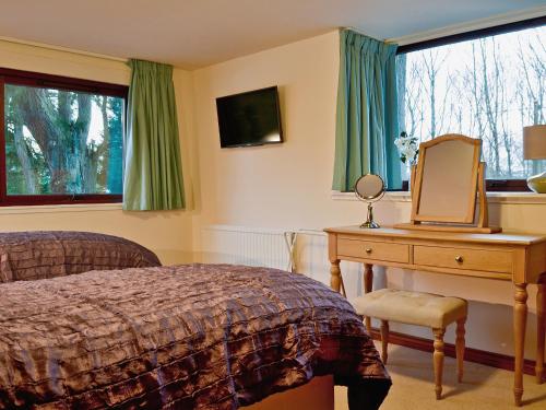 a bedroom with a bed and a desk with a laptop on it at The Gregorton Coachhouse in Rattray