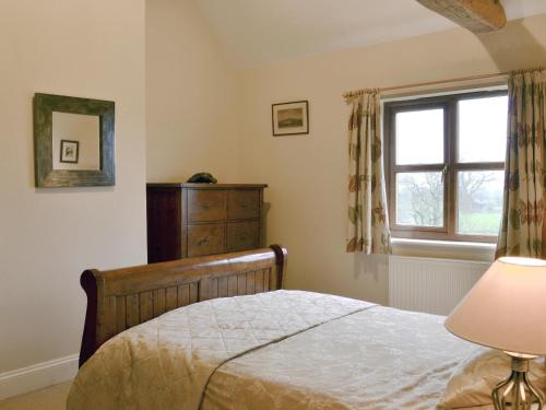 a bedroom with a bed and a window and a dresser at Blackthorn Cottage in Norton Disney