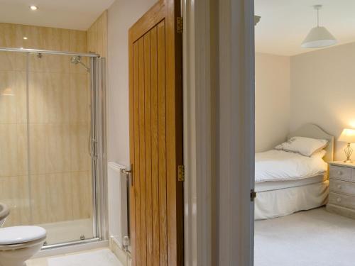 a bathroom with a shower and a toilet and a bed at Blackthorn Cottage in Norton Disney