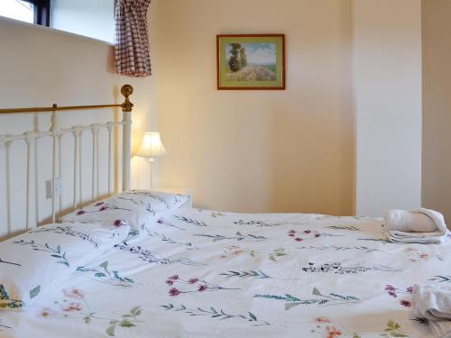 ein Bett mit einer weißen Tagesdecke mit Blumen darauf in der Unterkunft The Old Haybarn in Long Sutton