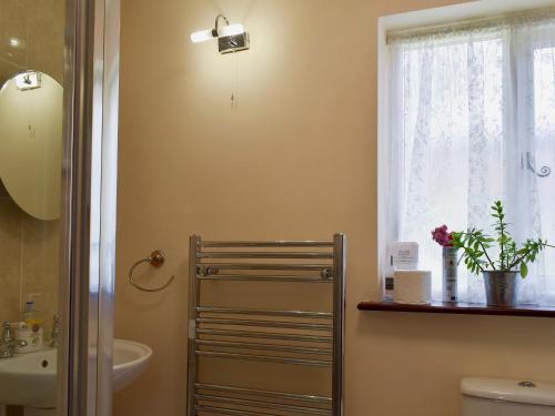 a bathroom with a toilet and a sink and a window at The Dairy in Burscough