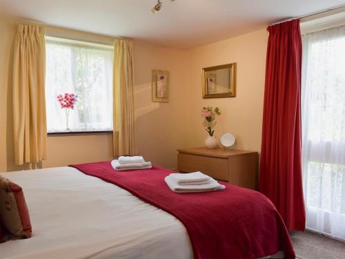 a bedroom with a bed with a red blanket on it at The Dairy in Burscough