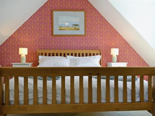 a bedroom with a wooden bed with a red wall at Loch Shore Cottage in Dornie