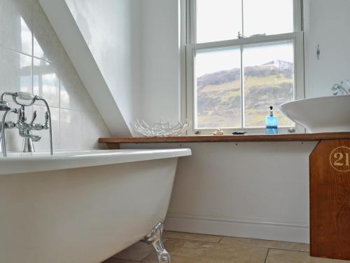baño con bañera, lavabo y ventana en Loch Shore Cottage en Dornie