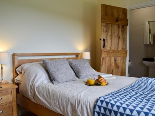 Una cama con una bandeja de fruta y una bebida. en Hoppers Cottage en Ticehurst