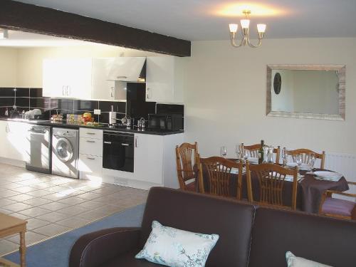 a living room and kitchen with a couch and a table at Jubilee Cottage in Pyworthy