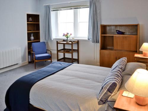 a bedroom with a bed and a chair and a window at Seaview Cottage - 27991 in Dunure