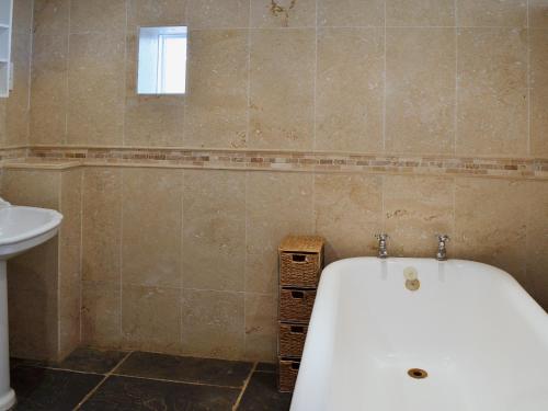 a bathroom with a bath tub and a sink at Brook Barn in Ellingham