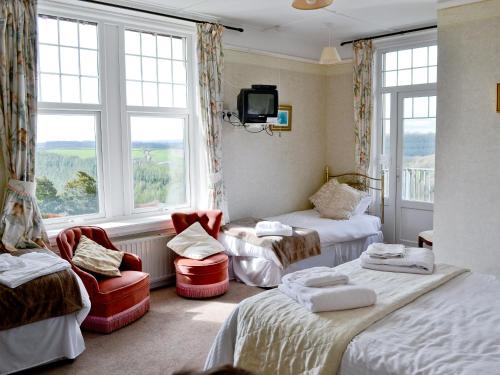 a room with two beds and a tv and windows at Beaford House in Beaford