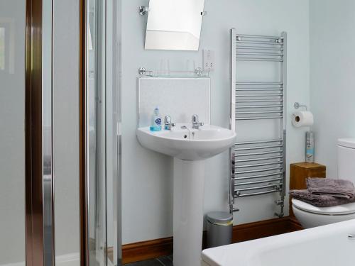 a white bathroom with a sink and a toilet at Mill Barn in Burnsall