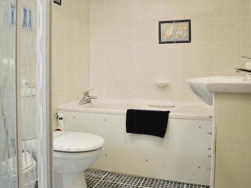 a white bathroom with a toilet and a sink at Granary Cottage in Saint Twynnells