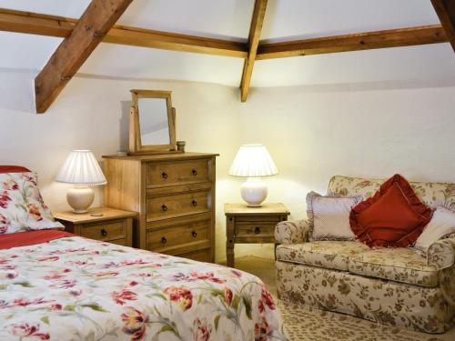 a bedroom with a bed and a chair and two lamps at Granary Cottage in Saint Twynnells