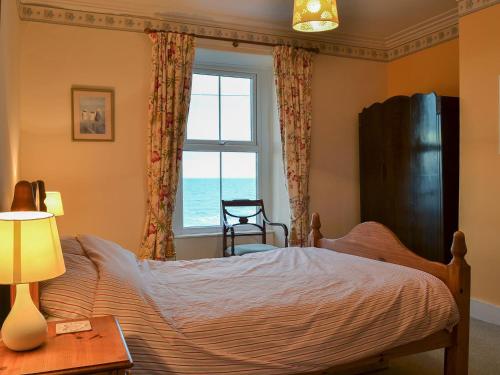 a bedroom with a bed and a window with the ocean at Shingle Cottage in Seascale