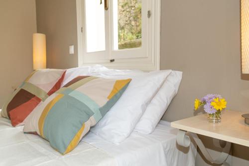 een bed met kleurrijke kussens en een raam bij Leeward Suite @ Fiscardo Waterfront in Fiskardho
