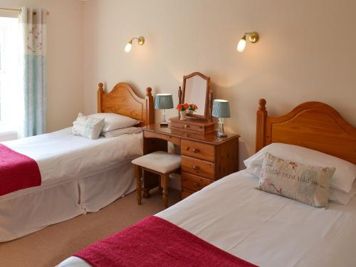 1 dormitorio con 2 camas y escritorio con espejo en Meadow Cottage - 26912, en Saint Issey