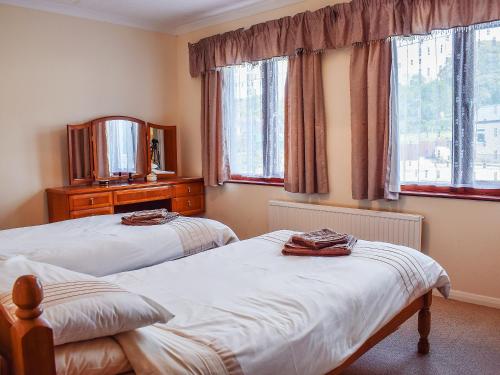um quarto com 2 camas, um espelho e janelas em Erwlon em Rhyd Owen