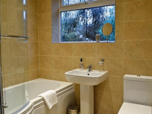 uma casa de banho com um lavatório, uma banheira e um WC. em Lake View em Bowness-on-Windermere