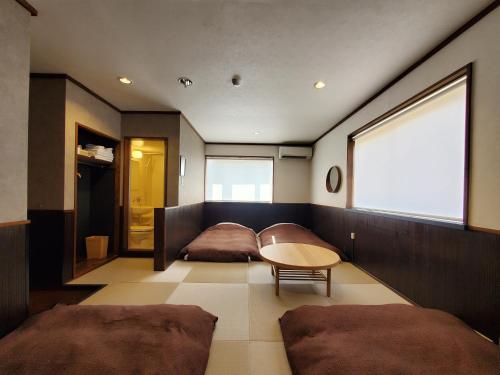 a room with two beds and a table and a window at 久住高原 赤川温泉スパージュ-Spaju in Taketa