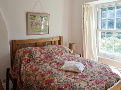 a bedroom with a bed with a colorful bedspread at Woodburn Cottage in Soutergate