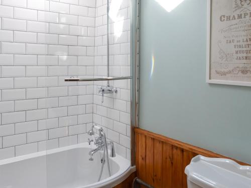 a bathroom with a white tub and a toilet at Woodburn Cottage in Soutergate