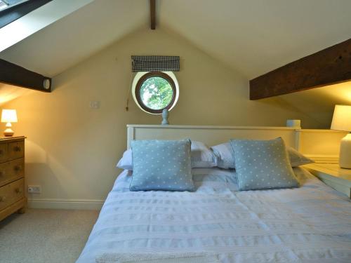 ein Schlafzimmer mit einem Bett mit blauen Kissen und einem Fenster in der Unterkunft The Pigsty Cottage E2783 in Llanyblodwel