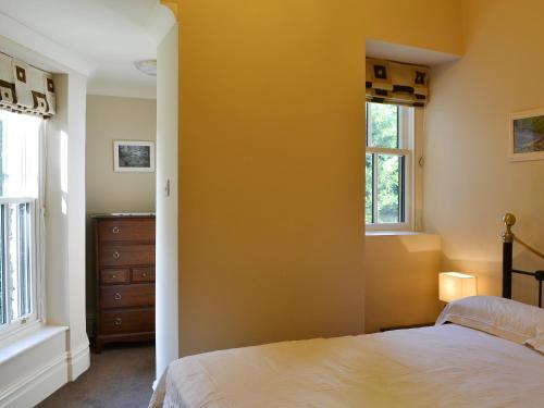 a bedroom with yellow walls and a bed and windows at Langdale Crag in Grasmere