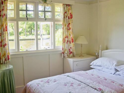 a bedroom with a bed and a window at Leisure Hour in Wroxham